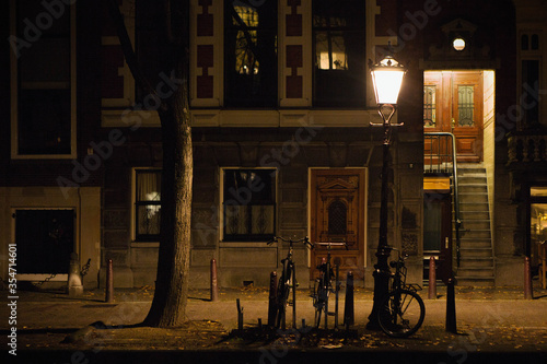 Canvas Print glimpse of a desert footpath in a residential district of Amsterdam city illuminated at night, bicycles parked in front of a house, Netherlands, Holland, Europe