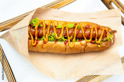 Hot dog with salad and cucumbers with tomato ketchup and mustard on white background. Tasty and beautiful fast food on a light back.