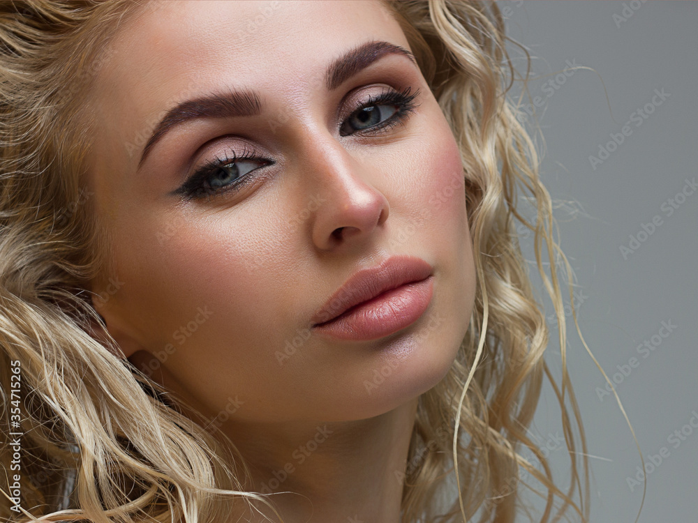 Fototapeta premium Sexy beauty face. Glamour portrait of beautiful woman model with fresh daily makeup. Fashion shiny highlighter on skin, sexy gloss lips make-up and perfect eyebrows. Natural beauty