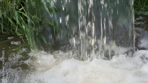 Close-up of a waterfall of water from a pipe with splashes and bubbling water in slow motion video.