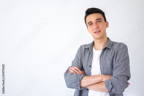 Positive guy crossed his arms and proudly looks at the camera Guy on a gray background. Copy space © marselmansuro