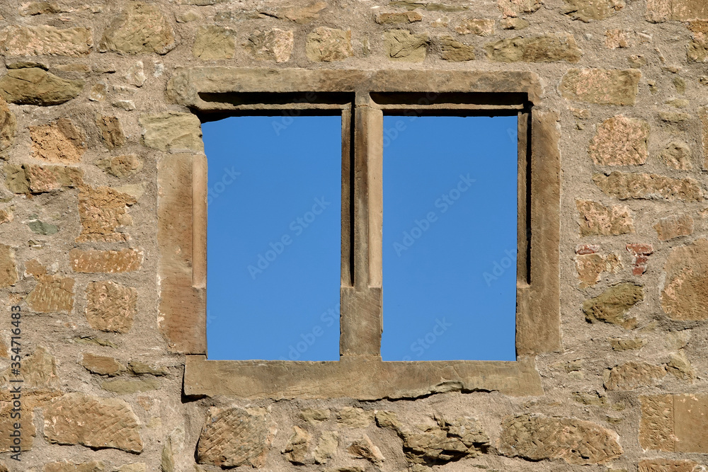 Brown window in a brick castle, photographed full frame, blue sky, deep perspective. Germany.