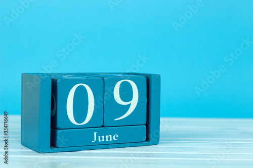 wooden calendar with the date of June 9 on a blue wooden background, Coral Triangle Day, International Accreditation Day, World Pet Memorial Day, International Archives Day, International Friends Day