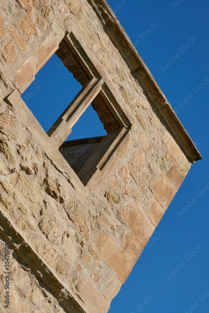 Brown window in a brick castle with a blue sky, sloping but symmetrical. Germany.