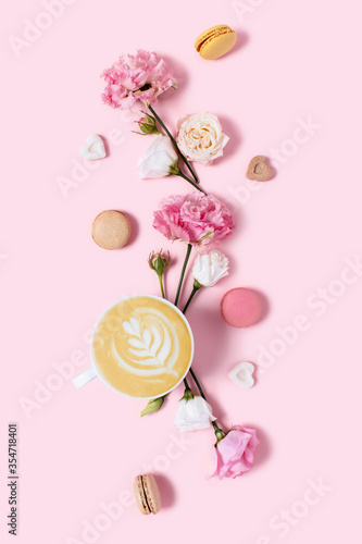Pink holiday card. Delicious cappuccino in flowers and macaroons on a pink background. Morning positive emotions.
