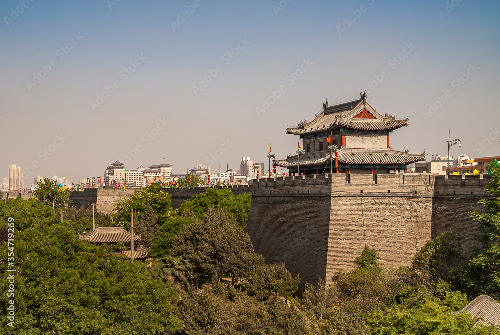 Obraz premium Xian, China - April 30, 2010: North Gate of Huancheng City Wall. Wide shot of small gray tower building in traditional Chinese architecture just east of gate under blue smog sky. Red ornaments and gre