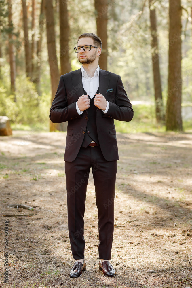 man in a dark suit posing in the forest. man in a dark suit posing in the forest.