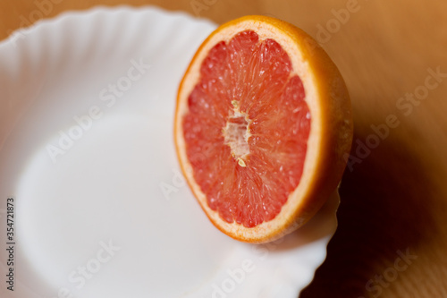 Somewhat old and dried grapefruit cut in half on white saucer.