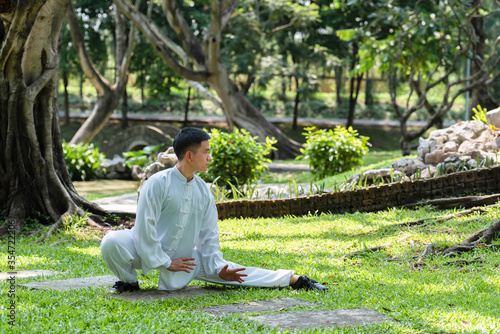 Young man practicing traditional Tai Chi Chuan, Tai Ji and Qi gong in the park for healthy, traditional chinese martial arts concept.