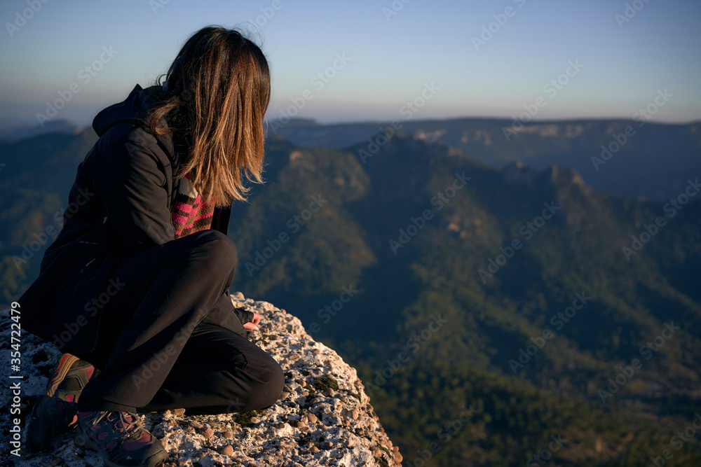 Young woman on the top of a mountain staring at the horizon. Concept of lifestyle and nature. Long shot.