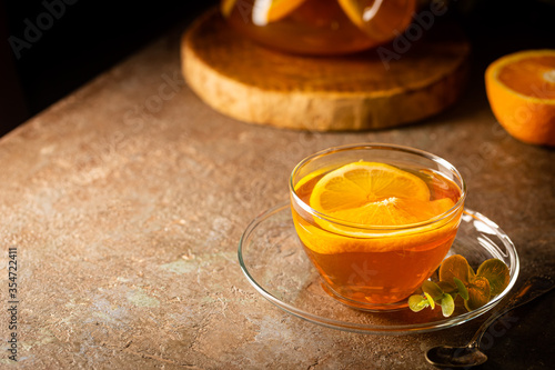 Glass teapot with hot citrus tea from oranges, lemons and limes, healthy drink on dark background