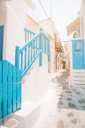 Fototapeta Naklejka Na Ścianę i Meble -  The narrow streets of the island with blue balconies, stairs and flowers.