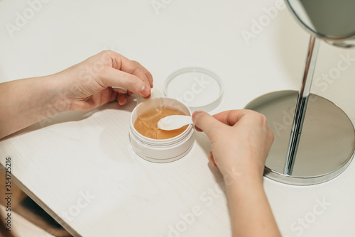 A young woman takes a spatula silicone patches under the eyes from bruises and bags. Beauty treatments, facial skin care, beauty secrets. White background.