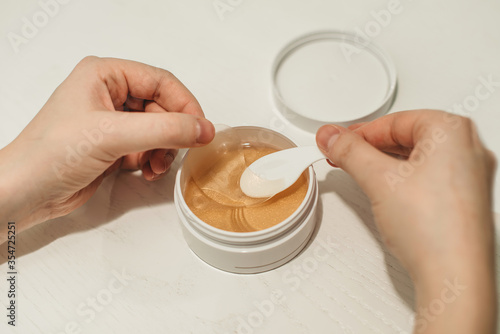 A young woman takes a spatula silicone patches under the eyes from bruises and bags. Beauty treatments, facial skin care, beauty secrets. White background.