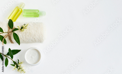 The concept of spa treatment. Natural / organic spa cosmetics, towel, cream, green leaves and flowers on a white background. Spa background with place for text, flat lay, top view