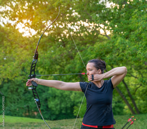 Fotografija attractive sports woman in archery, arrows and bow in action