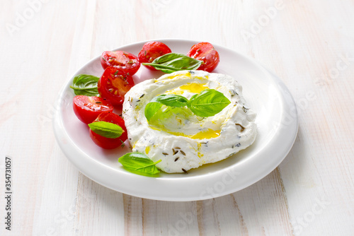 Homemade cream cheese ( labneh) wiht cherry tomatoes, basil and olive oil close up