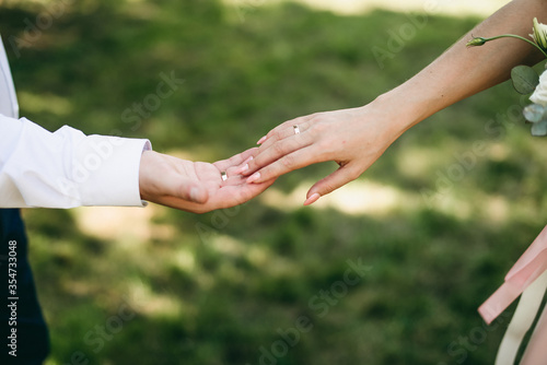 Brides hands touch each other on green grass background in summer street. © lesia17