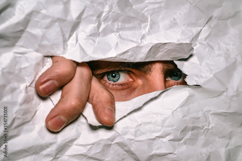 Foto Man's blue eyes spying through a hole