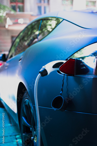 Charging modern electric car with cable plug inserted ir public parking lot