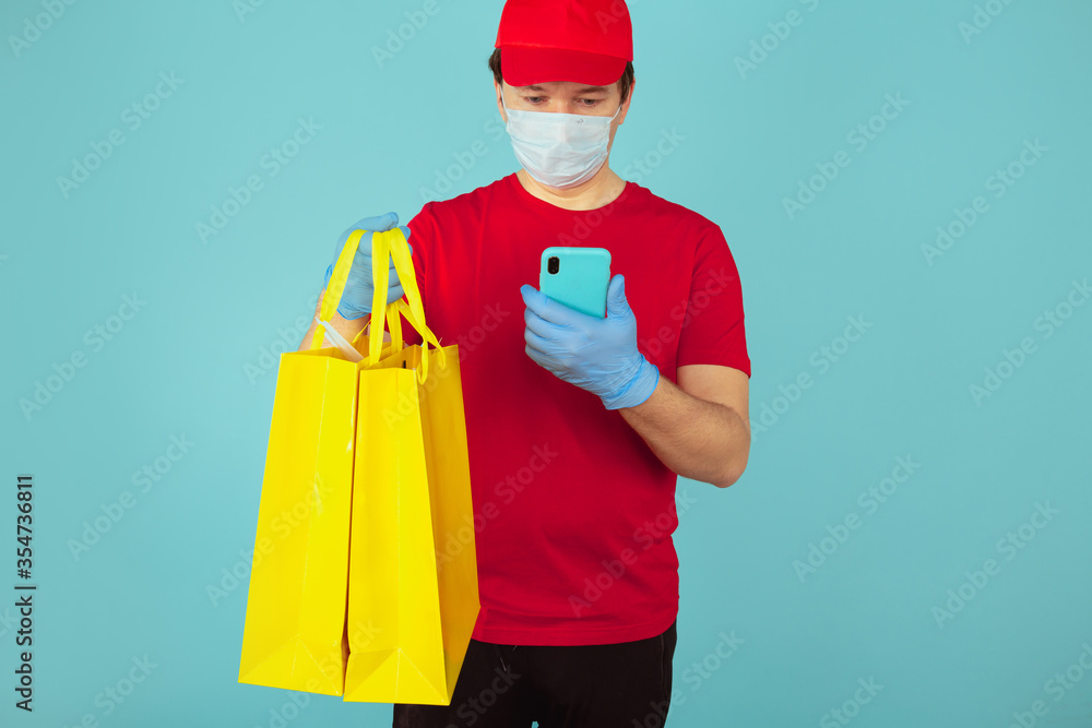 Delivery clothes in the shopping bag. Man in the mask with the order in the yellow bag Delivery clothes in the shopping bag. Man in the mask with the order in the yellow bag