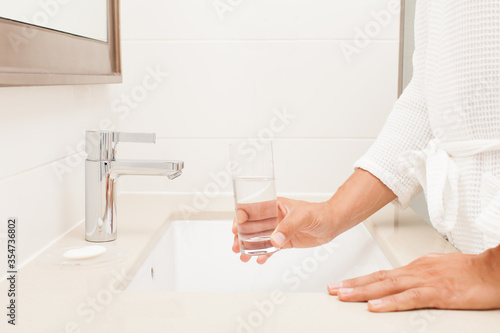 man arms closeup with glass water in bathroom