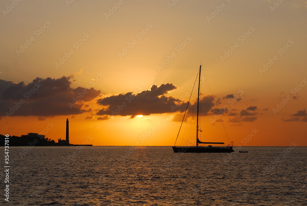 Sailing yacht and Lighthouse in the sun rays early in the morning