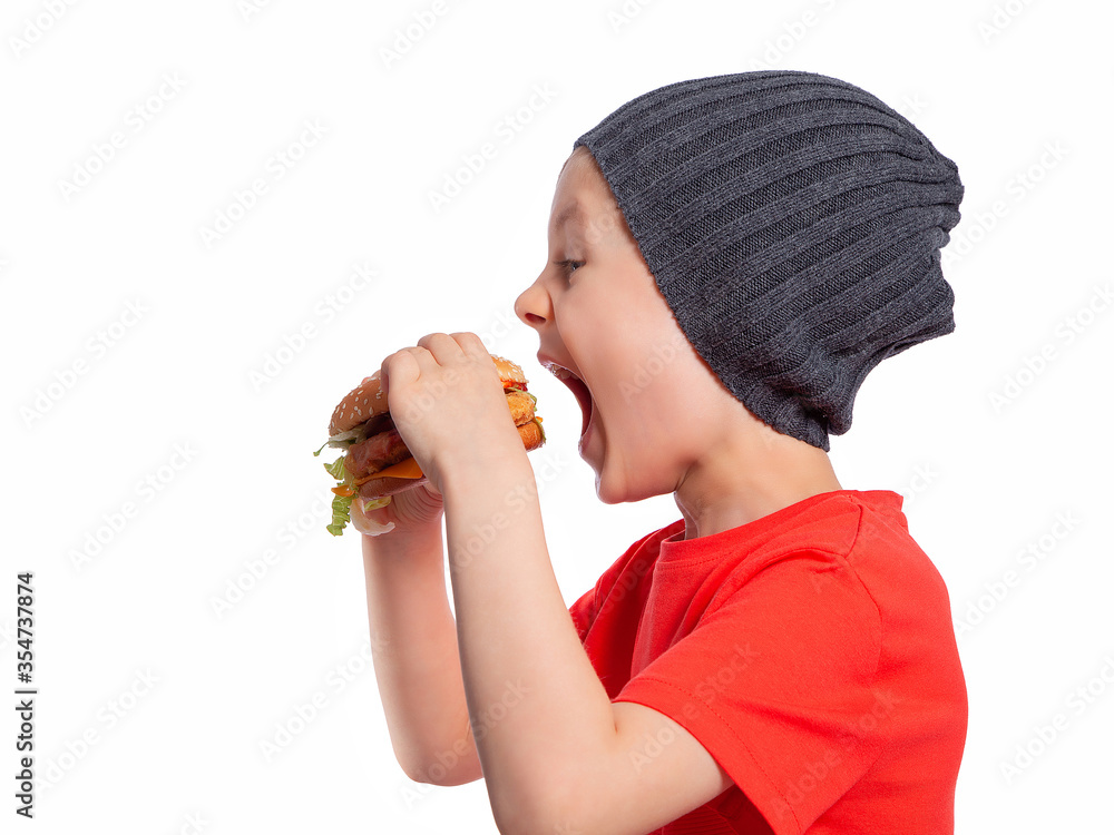 The child takes an appetising bite of a hamburger. A beautiful European boy 6 years old is going to eat fast food. Happy child. Snack. Favorite children's food. The child takes an appetising bite of a hamburger. A beautiful European boy 6 years old is going to eat fast food. Happy child. Snack. Favorite children's food.