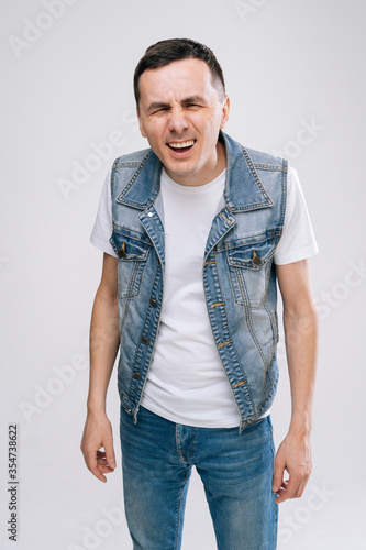 Handsome young man with in denim clothes raising hands in frustrated gesture feeling unsure in something, standing over white isolated background. What are you talking about, I can not figure it out