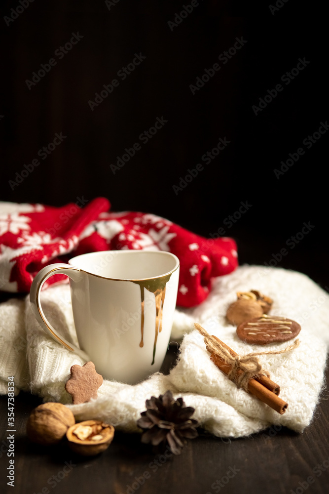 White cup with tea, knitted scarf and nuts near, on wood background White cup with tea, knitted scarf and nuts near, on wood background