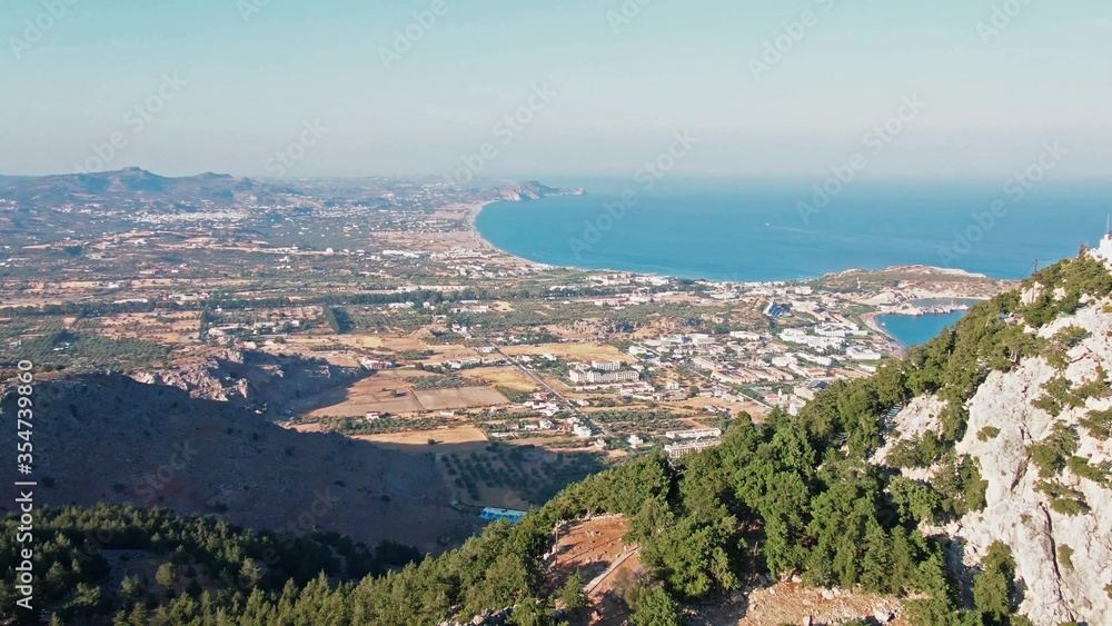View to Kolympia from Tsambika church on Rhodes island, Dodecanese, Greece. Birds eye view 4k aerial footage from drone. Sunny panorama with clear blue water. South Europe.