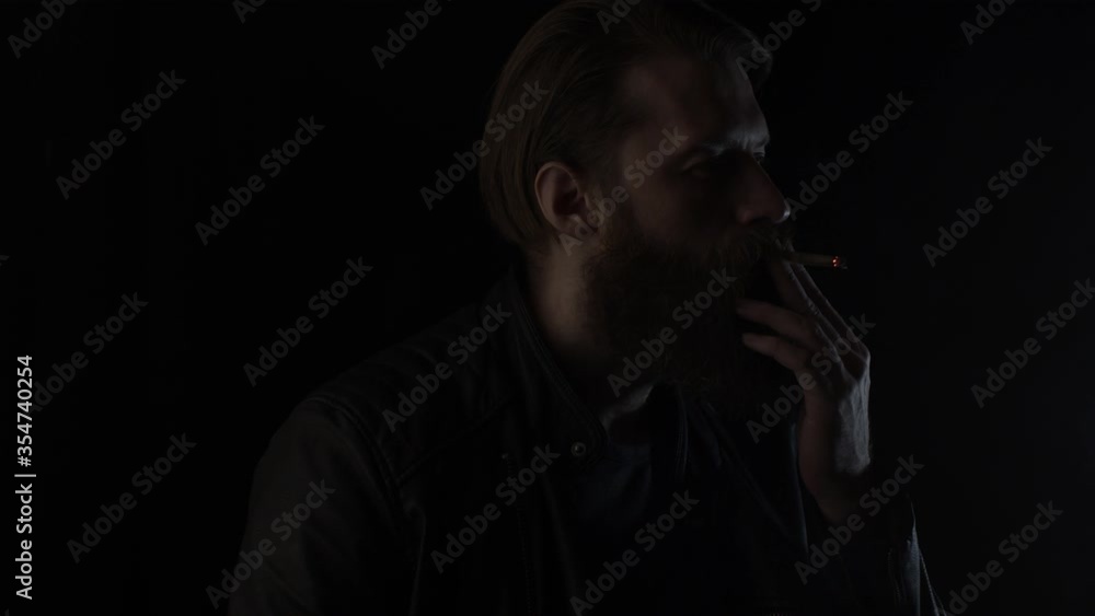 Smoking and drinking bearded man on black. Slow motion Smoking and drinking bearded man on black. Slow motion