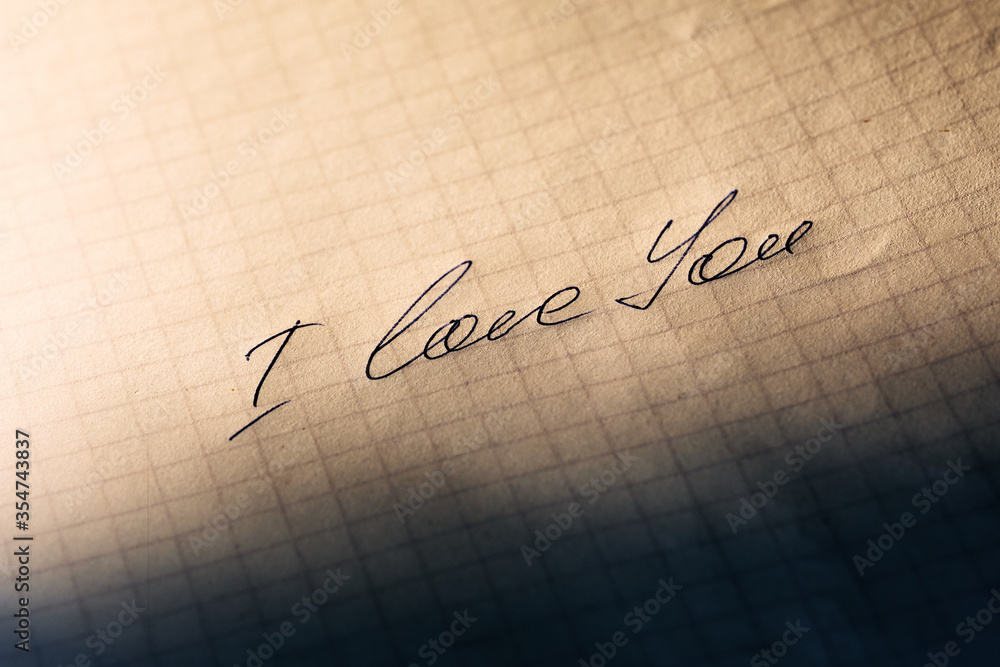 The phrase I love you, handwritten with a beautiful underline on a squared sheet. Manifestation of love and feelings. 
