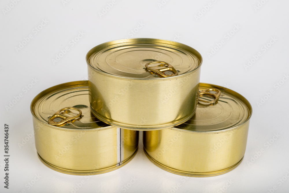 A metal tin cans on a white table. Food with a long shelf life. A metal tin cans on a white table. Food with a long shelf life.