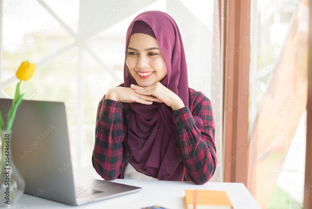 Muslim woman with hijab is working with laptop computer in coffee shop Muslim woman with hijab is working with laptop computer in coffee shop