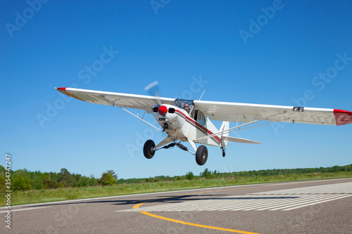 Small single engine airplane takes off from a municipal airfield in rural Minnesota