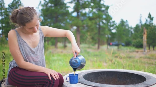 Campsite with young woman closeup drinking hot tea from teapot kettle on grill in Flaming Gorge, Utah USA summer camground in morning photo