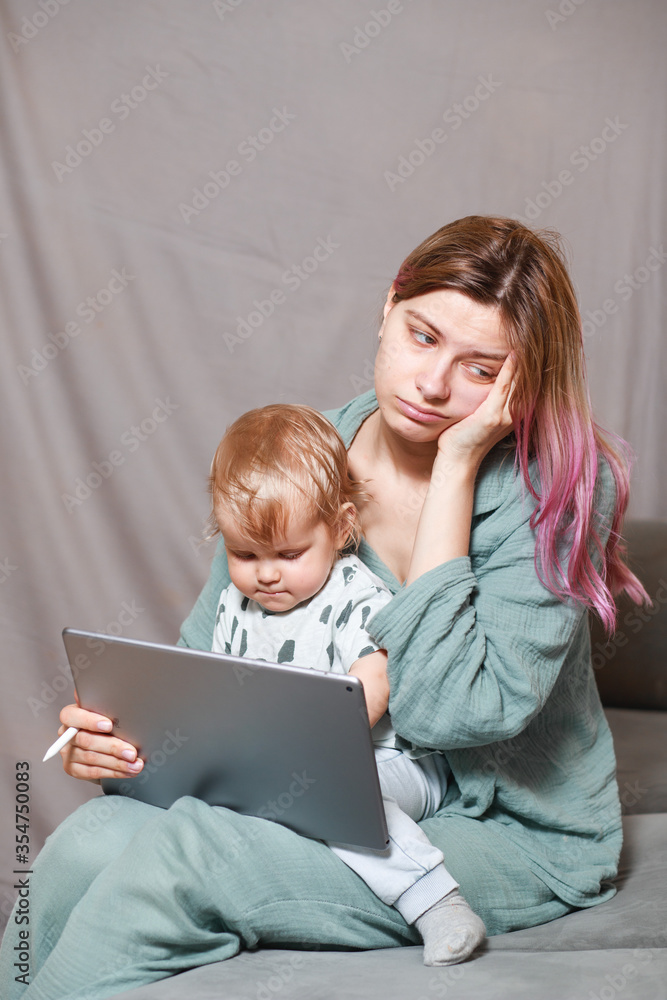 Stay at home, mom works remotely on a laptop computer, taking care of her child. A young mother on maternity leave is trying to work as a freelancer with a baby. Stay at home, mom works remotely on a laptop computer, taking care of her child. A young mother on maternity leave is trying to work as a freelancer with a baby.