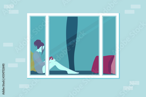 The girl is sitting at home and reading a book. View through the window. Cozy lounger near the window with pillows. Plastic window on a brick wall