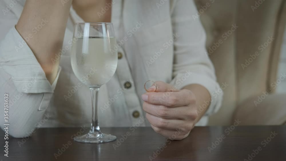 Betrayal in family. A woman throws a wedding ring into a glass of wine. Betrayal in family. A woman throws a wedding ring into a glass of wine.