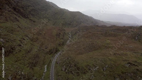 Aerial shot of car on winding road through mountains, drone flying forward towards vehicle - Southwestern Iceland, Ireland photo