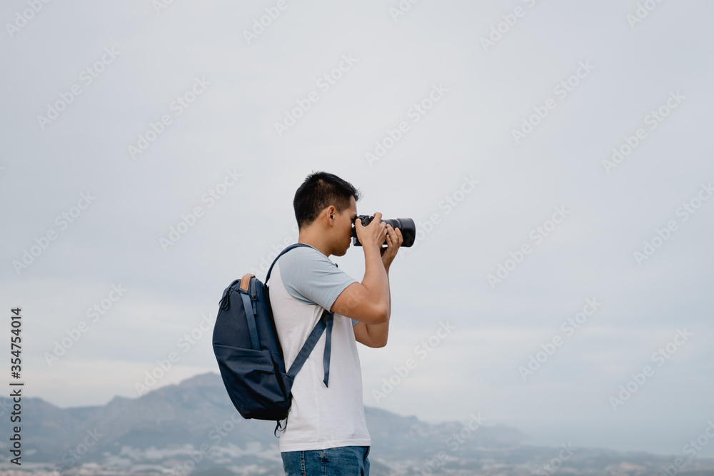joven fotógrafo con mochila azul realizando fotos con una cámara con teleobjetivo