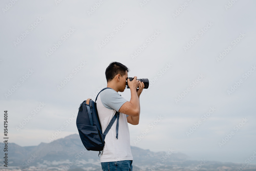 joven fotógrafo con mochila azul realizando fotos con una cámara con teleobjetivo joven fotógrafo con mochila azul realizando fotos con una cámara con teleobjetivo