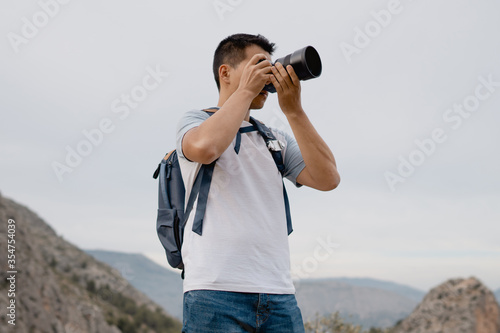 Canvas Print hombre joven con cámara grande profesional haciendo fotos al paisaje