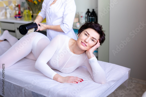 Lymphatic drainage massage LPG or R-sleek apparatus process. Woman in white suit getting anti cellulite massage in a beauty salon. Skin and body care