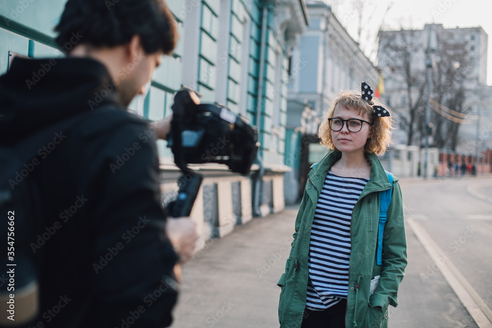A girl makes a video blog with a cameraman on the street.