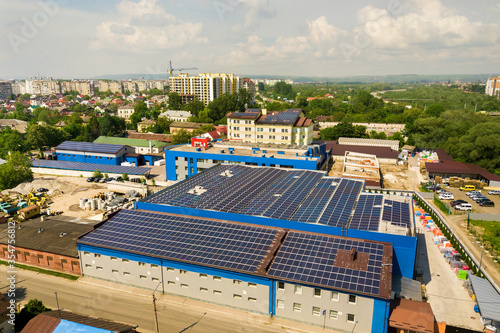 Aerial view of many photo voltaic solar panels mounted of industrial building roof. © bilanol