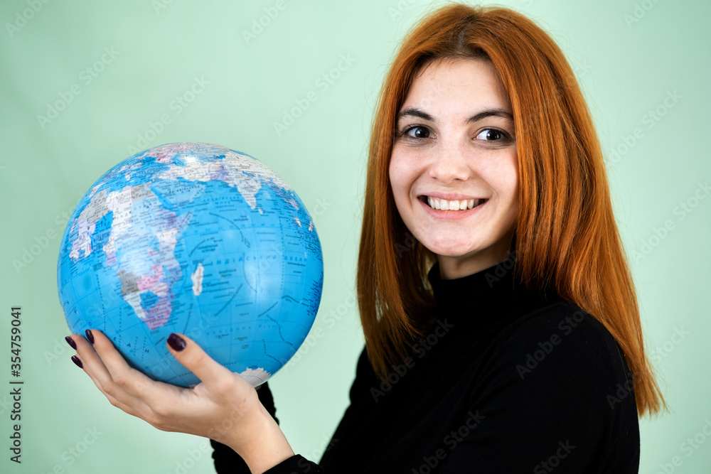 Portrait of a happy young woman holding geographic globe of the world in her hands. Travel destination and planet protection concept. Portrait of a happy young woman holding geographic globe of the world in her hands. Travel destination and planet protection concept.