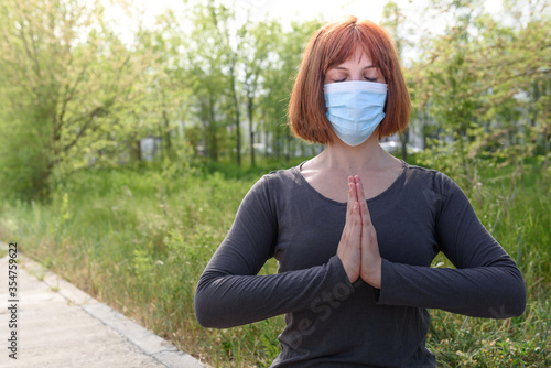 Girl in lotus position with sirurgical mask in nature background.