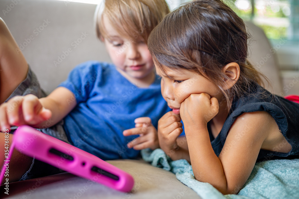 Caucasian boy and Asian girl play and learn on electronic tablet device Caucasian boy and Asian girl play and learn on electronic tablet device